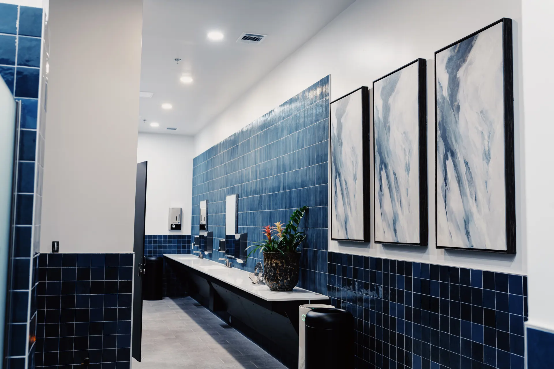 The men's locker room at THIS Gym — navy tile, grooming stations, and private showers — image 2 of 3